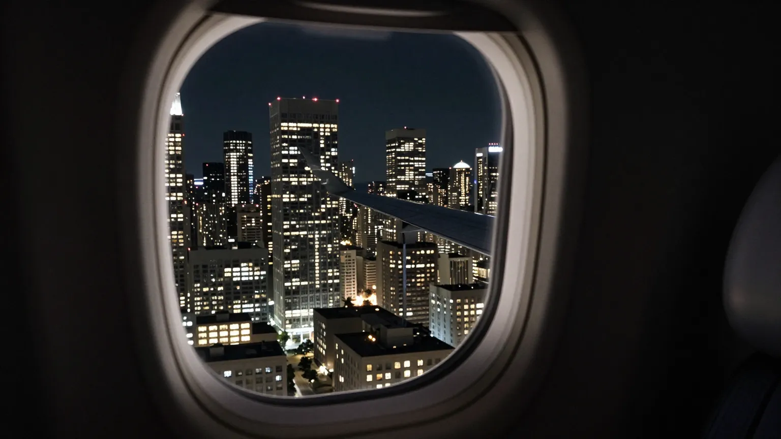Dense city skyline at night seen from a private jet window